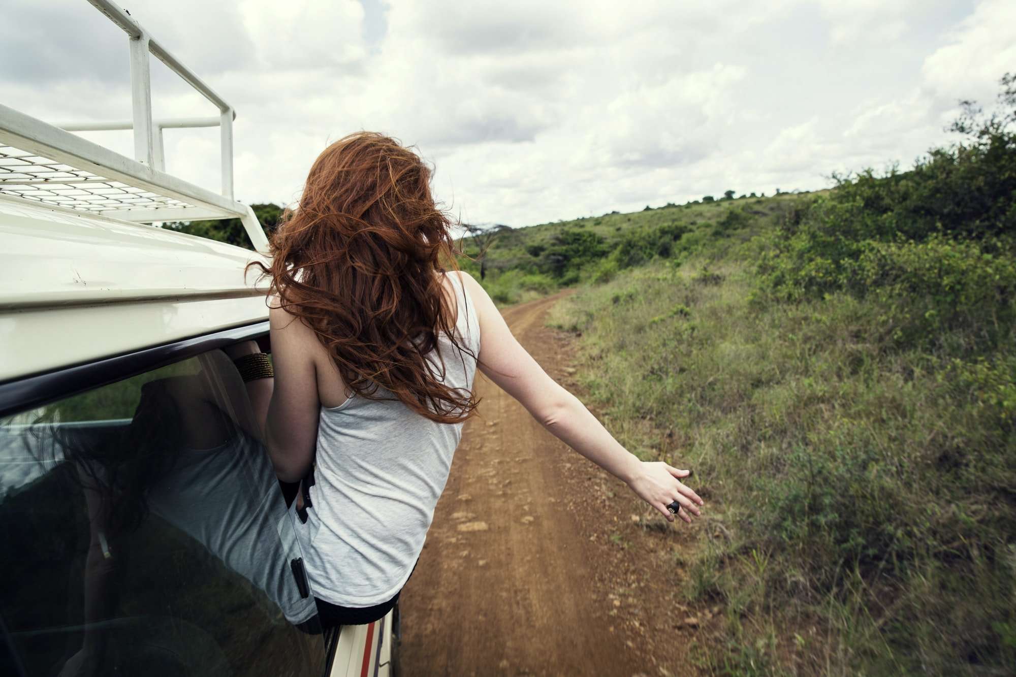 Woman sitting on door of vehicle in wildlife park, Nairobi, Kenya